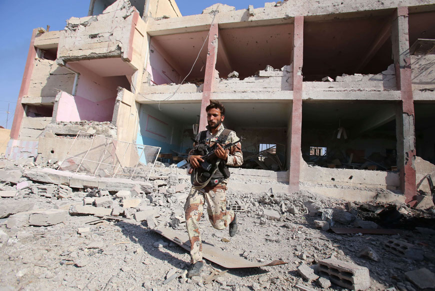 A member of the Syrian regime forces runs near destroyed buildings in the northeastern Syrian city of Hasakeh on Monday (AFP photo)