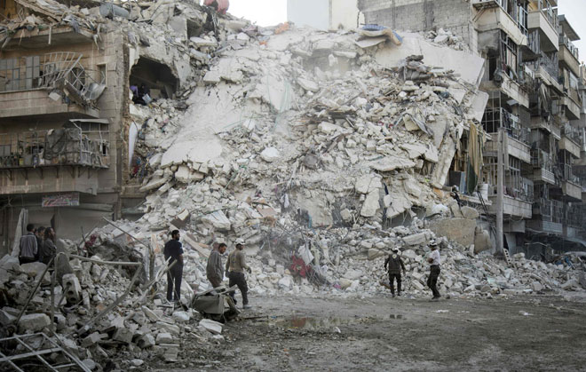 Members of the Syrian civil defence, known as the White Helmets, search for victims amid the rubble of a destroyed building following reported air strikes in the rebel-held Qatarji neighbourhood of the northern city of Aleppo, on Monday (AFP photo)