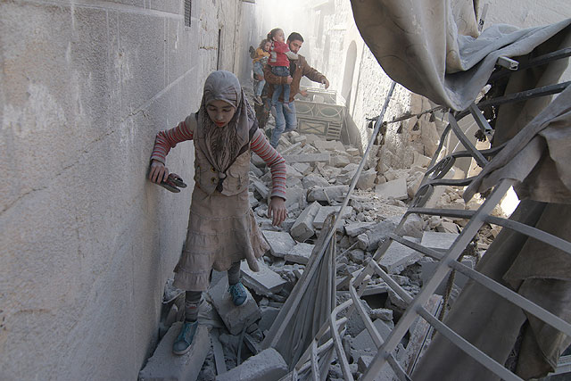 Civilians walk around the debris of damaged buildings after air strikes by warplanes reportedly belonging to Syrian and Russian forces over residential areas in Aleppo, Syria, on Thursday (Anadolu Agency photo)