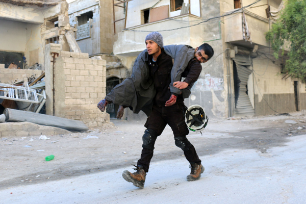 A Syrian civil defence volunteer, known as the White Helmets, carries an injured man on Saturday following a reported air strike on Aleppo’s rebel-held neighbourhood of Bab Al Nayrab (AFP photo)