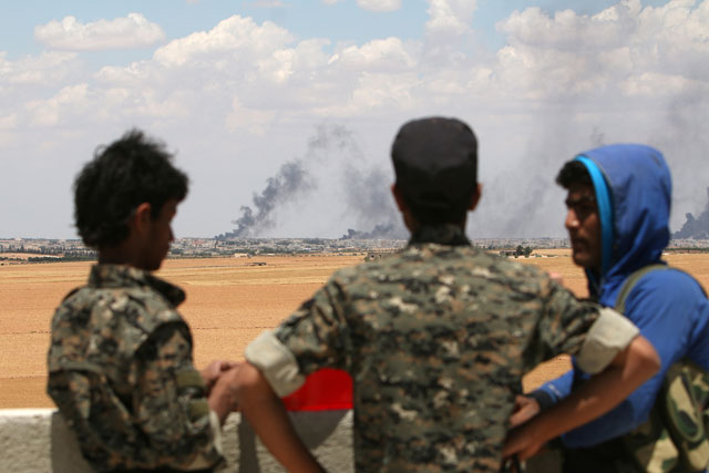 Manbij Military Council fighters stand at a checkout point overlooking rising smoke from Manbij city, Aleppo province, Syria on Wednesday (Reuters photo)