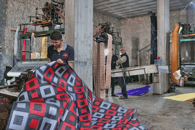 In this photo taken on June 1, men work at a factory making mats and rugs from recycled plastic, in Sarmada in Syria’s northwestern Idlib province  (AFP photo)