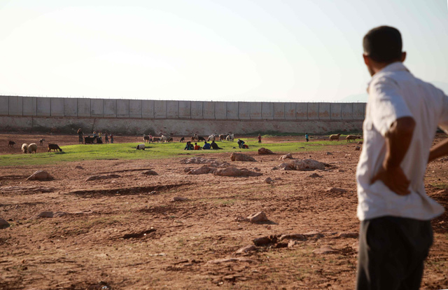 A displaced Syrian man looks towards the barbed-wire-topped concrete fence demarcating the border between Syria and Turkey, at a camp for displaced Syrians in Atme in the north-western Idlib province, near the borther with Turkey, on September 22 (ADP photo)