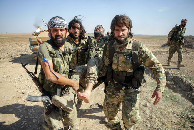 Turkish-baked Syrian fighters carry a fellow wounded fighter near the Syrian border town of Tal Abyad on Saturday, as Turkey and its allies continue their assault on Kurdish-held border towns in north-eastern Syria (AFP photo)