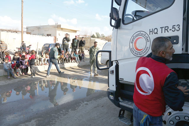 Syrian children sit on the curb of the street as they watch lorries from the Syrian Arab Red Crescent delivering aid to the town of Utaya in Eastern Ghouta on Wendesday (AFP photo)