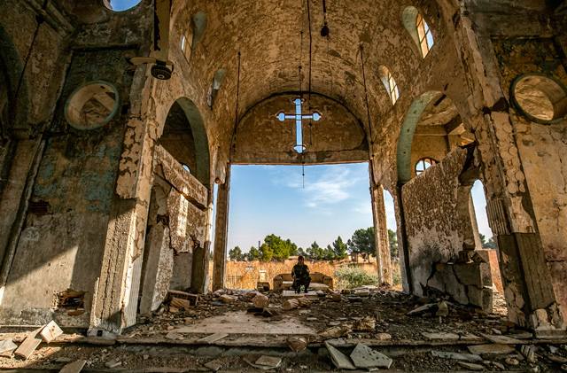 A member of the Khabur Guards Assyrian Syrian militia, affiliated with the Syrian Democratic Forces, sits in the ruins of the Assyrian Church of the Virgin Mary, which was previously destroyed by Daesh fighters, in the village of Tal Nasri south of the town of Tal Tamr in Syria’s north-eastern Hasakah province, on Friday (AFP photo)