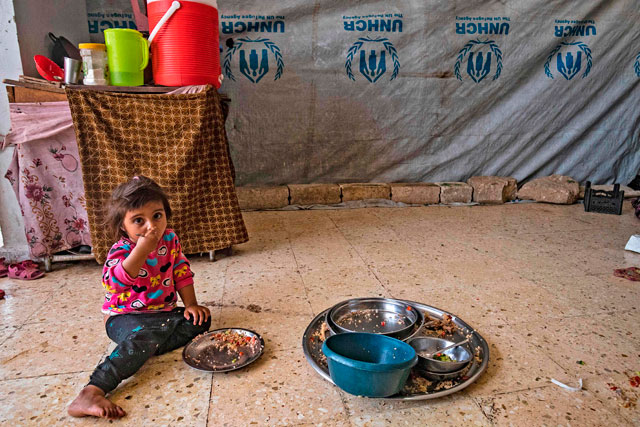 A girl eats on the floor of a school building where Syrians displaced from Ras Al Ain, a border town controlled by Turkey and its Syrian proxies, are staying in the city of Hasakeh on Thursday (AFP photo)