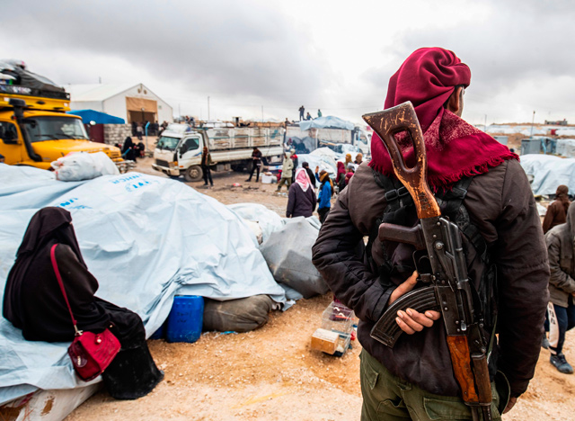 A member of Kurdish security forces watches as families load their belongings onto trucks before leaving the Kurdish-run Al Hol camp holding relatives of alleged Daesh group fighters, in the Al Hasakeh governorate in north-eastern Syria, on Monday  (AFP photo)