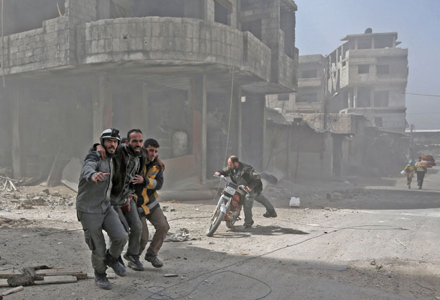 Volunteers from the Syrian civil defence help a man in Hammouriya during Syrian government shelling on rebel-held areas in the Eastern Ghouta region on the outskirts of the capital Damascus on Tuesday (AFP photo)
