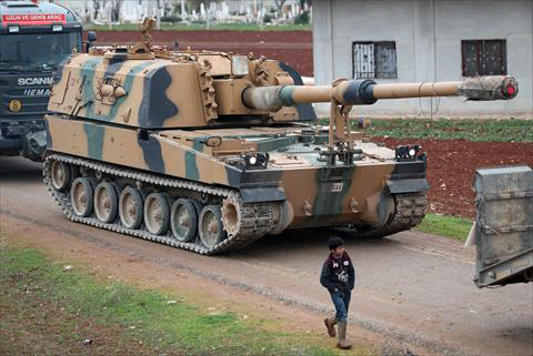 In this file photo taken on February 12, 2020, a child walks past a Turkish 155mm self-propelled artillery gun in the town of Binnish in Syria's northwestern province of Idlib, near the Syria-Turkey border (AFP photo)