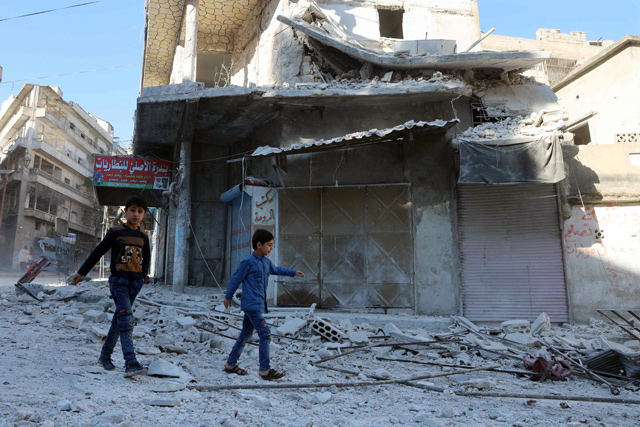 People walk past debris at the site of shelling in the Syrian town of Ariha in the rebel-held northwestern province of Idlib on Wednesday (AFP photo)