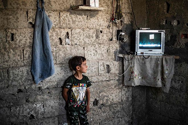 A Syrian boy, displaced with his family from Deir Ezzor, watches inside the damaged building where she is living in Syria’s northern city of Raqqa, on June 18 (AFP photo)