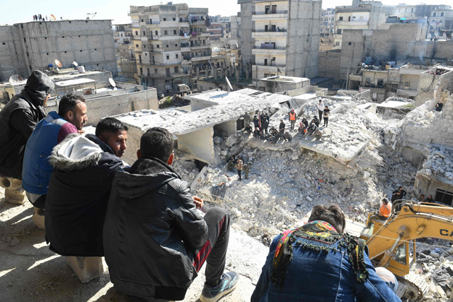 People watch as rescuers sift through the rubble of a building that collapsed in the northern Syrian city of Aleppo, on Sunday (AFP photo)