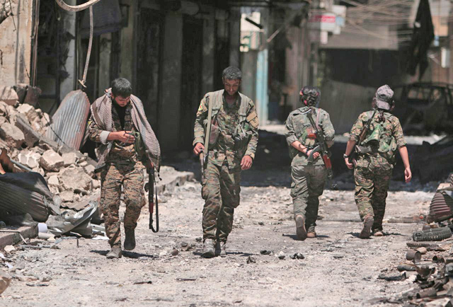Syrian Democratic Forces fighters walk on the rubble of damaged shops and buildings in the city of Manbij, in Aleppo governorate, Syria, on  August 10, 2016 (Reuters photo)