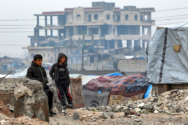 Boys stand by tents pitched near a building that was damaged by the February 6, 2023 earthquake that devastated northern Syria and Turkey, in the town of Jindayris in the northwest of Syria's Aleppo province on February 3 (AFP photo)