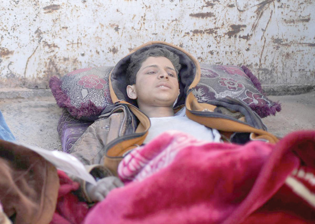 Hareth Najem, an Iraqi orphan, lies under a blanket in a truck, near the village of Baghouz, Deir Ezzor province, Syria, on Friday (Reuters photo)