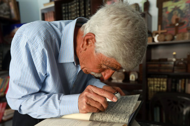 George Zaarour, a specialist in the Aramaic language, uses a magnifying glass to decipher Aramaic script in the Syrian mountain village of Maalula, in the Damascus region on May 13 (AFP photo)