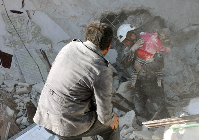 A civil defence team member carries the body of a girl as they carry out a search and rescue operation at the debris of a building after explosions were carried out with bomb-laden vehicles in Idlib, Syria, on Monday (Anadolu Agency photo)