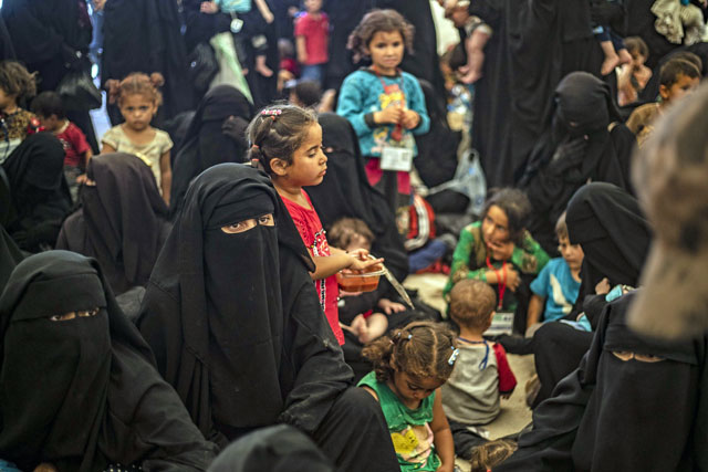 Displaced people gather before boarding a bus waiting outside Al Hol camp in north-eastern Syria’s Al Hasakeh governorate, on Monday (AFP photo)