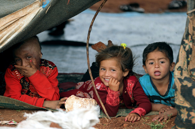 Displaced Syrian refugee children lie down on a mat on the floor in an olive grove at the north of Idlib countryside, Syria, on June 4 (Reuters photo)