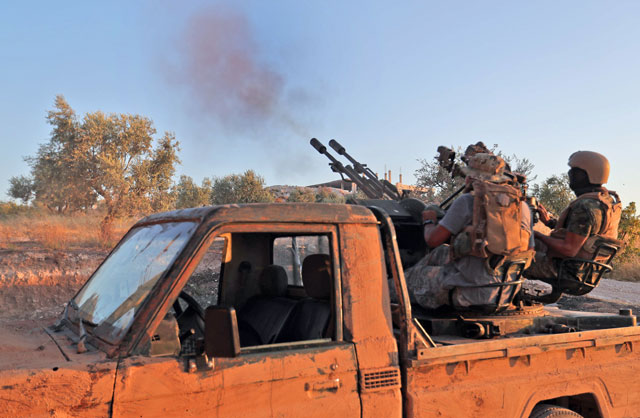  A fighter from the former Al Qaeda Syrian affiliate Hayat Tahrir Al Sham fires an anti-aircraft gun mounted on a pickup truck in Syria’s southern Idlib province on Wednesday (AFP photo) 
