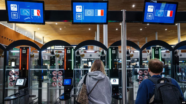 Police officers help passengers to go through a facial recognition verification system at Roissy-Charles de Gaulle Airport, north of Paris, on July 3 (AFP photo)