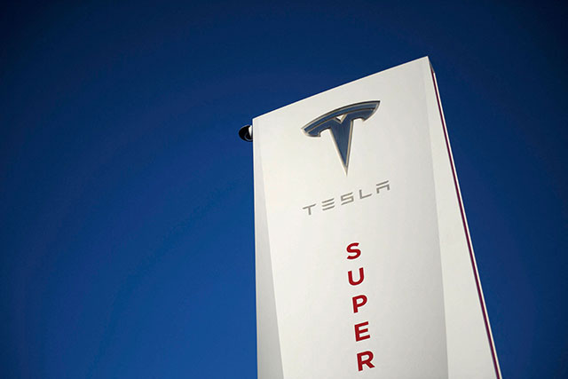 In this file photo taken on January 4, 2021, a Tesla logo is seen on signage at a Tesla Inc. supercharger station on in Hawthorne, California (AFP Photo)