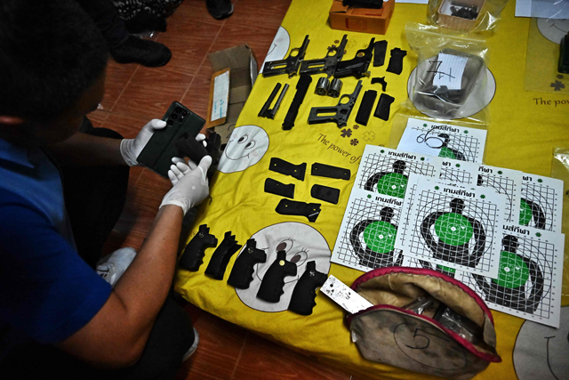 A forensic investigator looks at gun parts put on display at a home raided by Thai police in Bangkok on Thursday as part of a police crackdown on illegal gun sales following a shooting attack at Bangkok Siam Paragon mall (AFP photo)