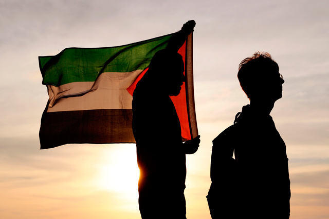 Peace activists wave a Palestinian flag during a protest near the southern Israeli kibbutz of Nahal Oz near the border with the Gaza Strip on Friday (AFP photo)