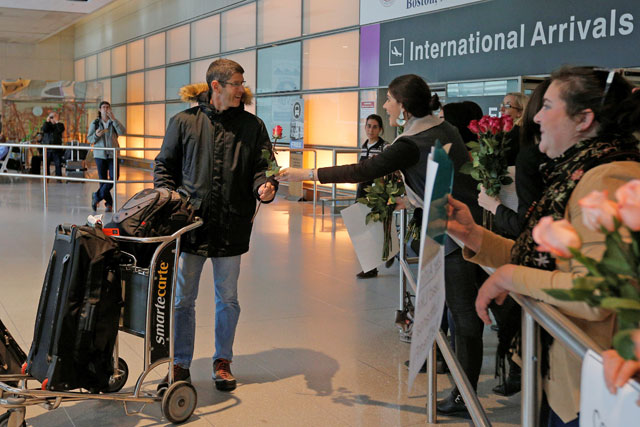 Laura Atlas Kravitz, an opponent of US President Donald Trump’s executive order travel ban, hands a flower to an arriving international traveller at Logan Airport in Boston, Massachusetts, on Friday (Reuters photo)