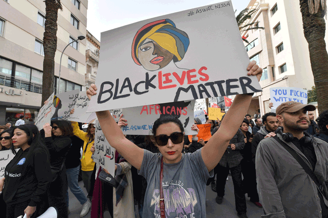 Protesters lift placards during a demonstration in Tunis on Saturday, against controversial remarks by the Tunisian president regarding illegal migrants that critics said were openly racist (AFP photo)