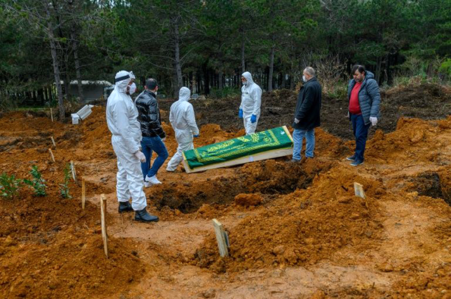 Officers and relatives prepare to bury a person who died from the coronavirus in Istanbul on Friday, at a cemetery opened by the government for victims of the COVID-19 pandemic (AFP photo)