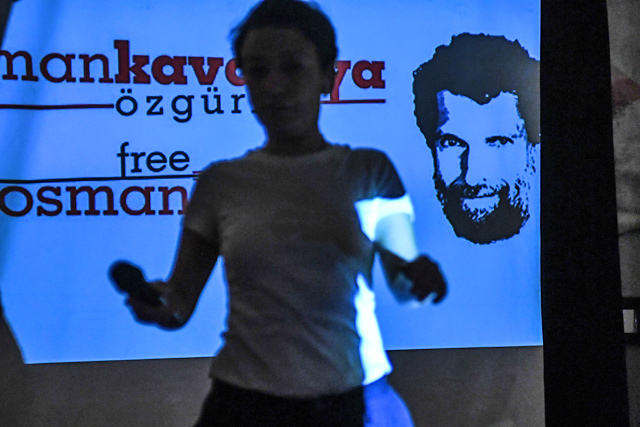In this file photo taken on October 31, 2018 a woman passes in front of a screen featuring jailed businessman and philanthropist Osman Kavala during a press conference of his lawyers (AFP photo)