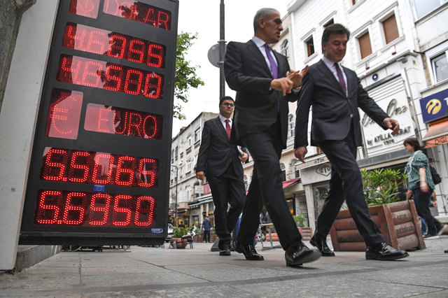People pass next to a board displaying US dollars and Euros exchange rates in Turkish liras in Istanbul on Wednesday  (AFP photo)