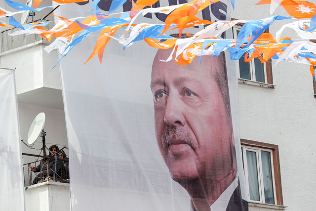 Women sit on a balcony next to a portrait of Turkish President Recep Tayyip Erdogan during an AKP (Justice and Development Party) campaign rally ahead of the local elections in Ankara, Turkey, on Thursday (AFP photo)