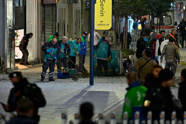 Municipal workers clean debris as Turkish policemen secure the area after a strong explosion of unknown origin shook the busy shopping street of Istiklal in Istanbul, on Sunday (AFP photo)