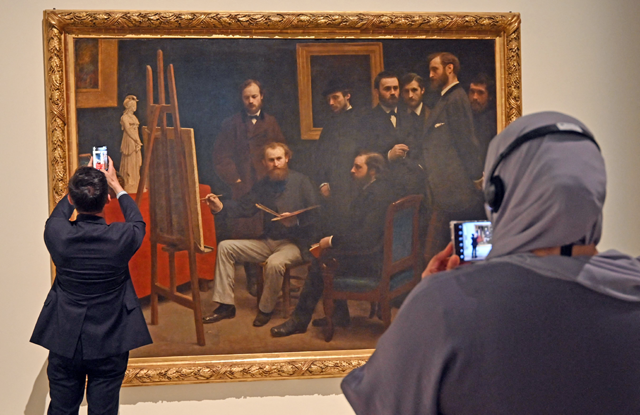 Visitors look at Henri Fantin-Latour’s masterpice A Studio at Les Batignolles displayed at the exhibition ‘Impressionism: Pathways to Modernity’ at the Louvre Museum Abu Dhabi in the Gulf emirate, on Tuesday (AFP photo)
