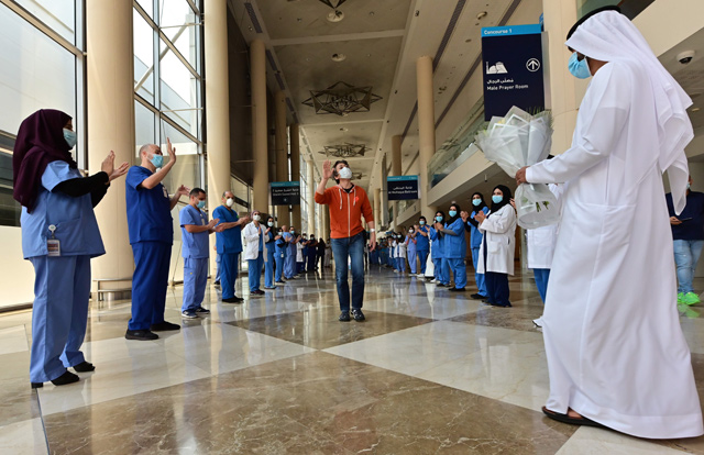 Hiroaki Fujita (centre) from Japan, the last patient at the temporary COVID-19 hospital built in downtown Dubai in the United Arabic Emirates, greets nurses and doctors as he leaves the facility, on Tuesday (AFP photo)