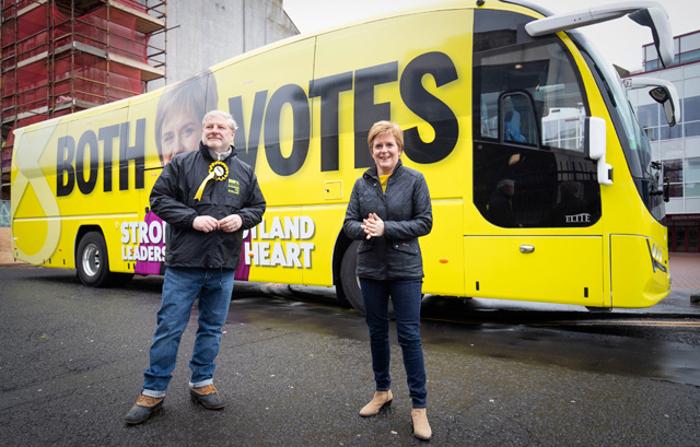 Scotland's First Minister and leader of the Scottish National Party (SNP) Nicola Sturgeon (right) walks past the campaign battle bus with SNP candidate Angus Robertson, during a campaign visit to LOVE Gorgie Farm in Edinburgh, Scotland on Tuesday, ahead of the upcoming Scottish parliament election which is to be held, on Thursday (AFP photo)