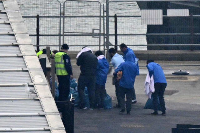 UK Border Force and Interforce security officers escort migrants at the Marina in Dover southeast England (AFP photo)