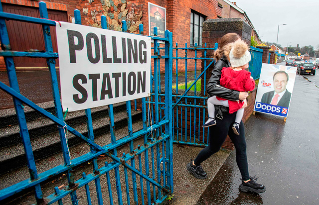 A voter passes an advertising board featuring an image of the Democratic Unionist Party's deputy leader Nigel Dodds, as she leaves from a polling station in Belfast, Northern Ireland, as Britain holds a general election, on Thursday (AFP photo)