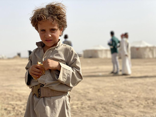 A five-year-old Yemeni boy stands outside a site for internally displaced people in Marib, Yemen, where conflict has forced thousands to flee (Photo courtesy of UNHCR)