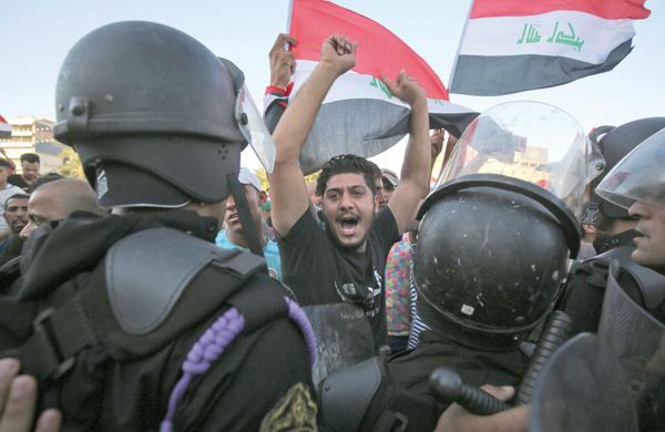 Iraqi protesters shout slogans and wave national flags as they face security forces during clashes at a demonstration against unemployment and a lack of basic services in the capital Baghdad's Tahrir Square on Friday (AFP photo)