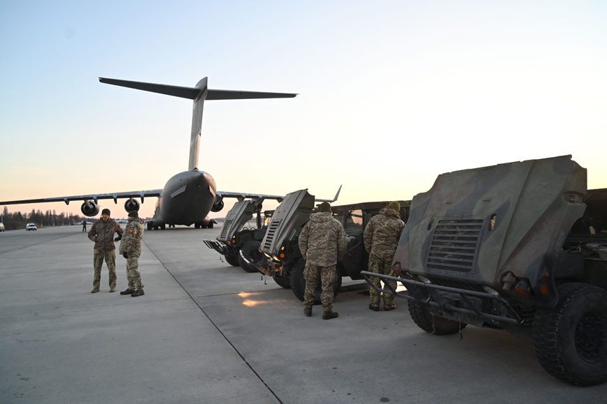 Servicemen of Ukrainian Military Forces examine the High Mobility Multipurpose Wheeled Vehicle military trucks shipped from Lithuania to Boryspil airport in Kyiv on Sunday (AFP photo)