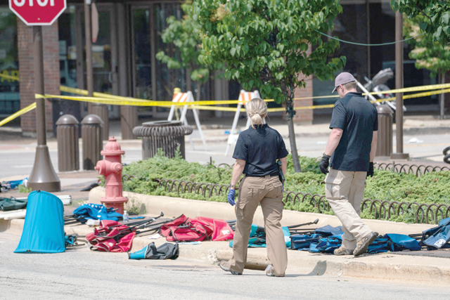 Law enforcement officers inspect chairs and belongings left behind at the scene of a mass shooting at a July 4th Parade in Highland Park, Illinois, on Tuesday (AFP photo)