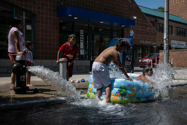 Children cool off with water from an open fire hydrant during a summer heat wave in the Bronx borough of New York on Thursday (AFP photo)