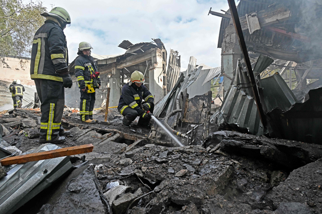 Firefighters put out a fire on the ruins of a destroyed electrical products plant following missile strikes in Kharkov on Tuesday (AFP photo)