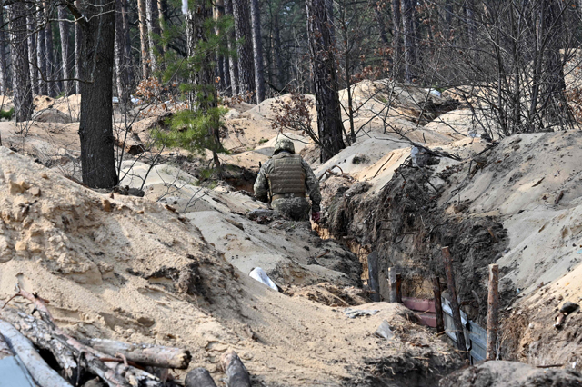 A Ukrainian serviceman walks along a trench along the front line, north of the Ukrainian capital of Kyiv, on Thursday (AFP photo)