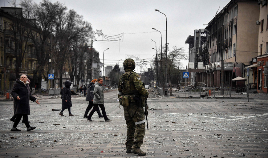 People pass by a Russian soldier in central Mariupol on Monday, as Russian troops intensify a campaign to take the strategic port city (AFP photo)