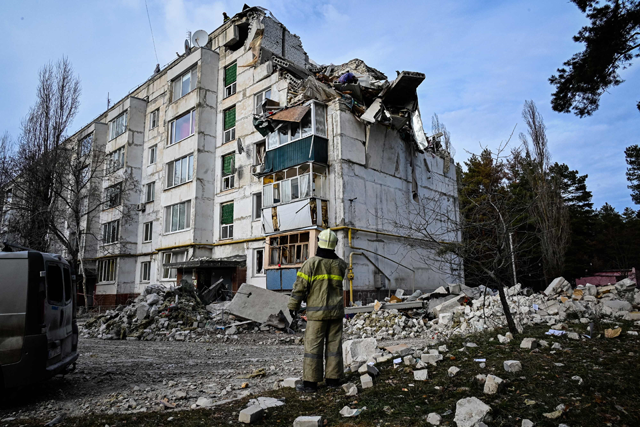 A rescuer looks at a residential building damaged by a missile attack in the village of Kluhyno-Bashkyrivka, Kharkiv region on Friday, amid the Russian invasion of Ukraine (AFP photo)